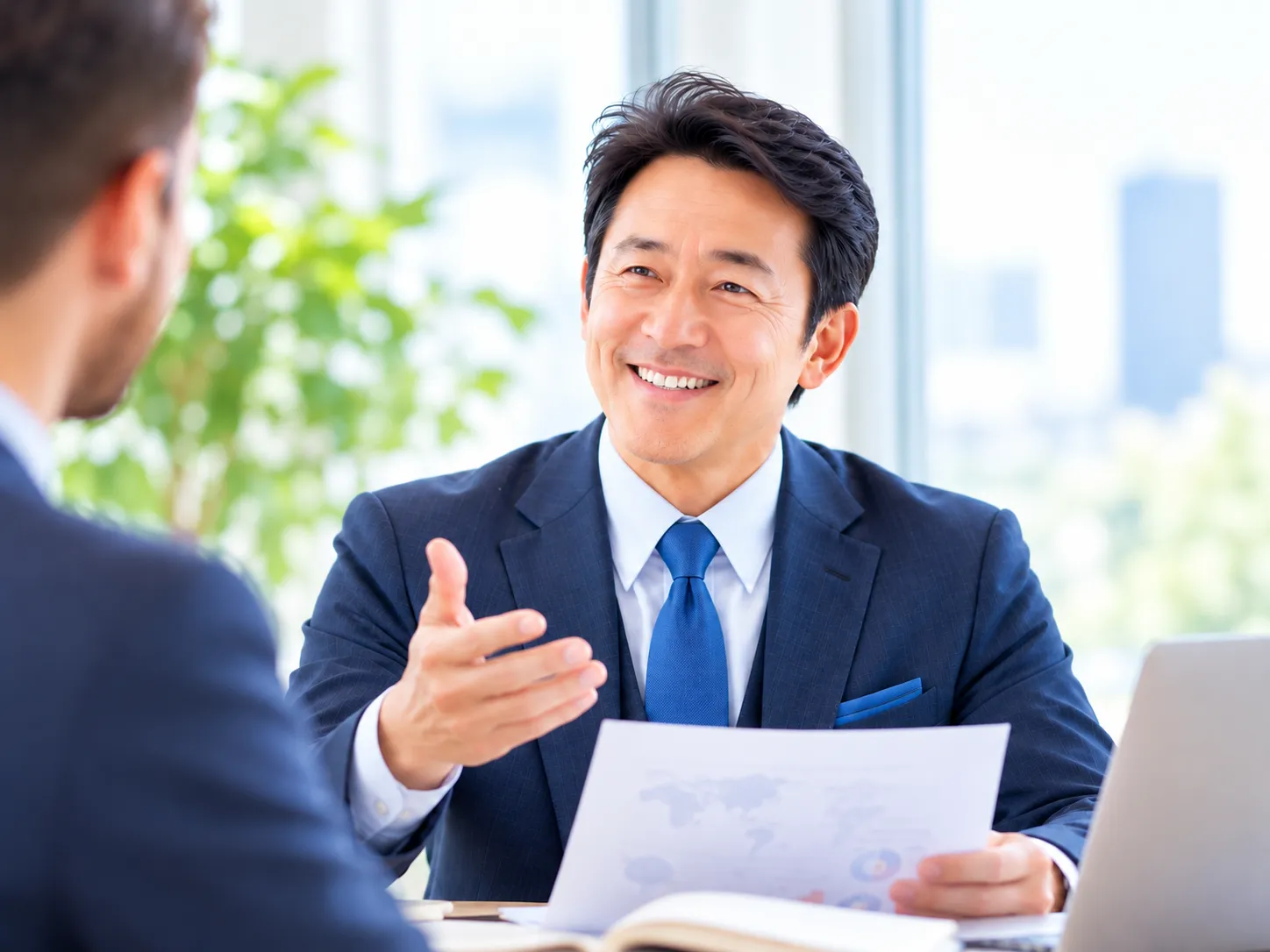 明るいオフィスで笑顔で会話するスーツ姿の男性